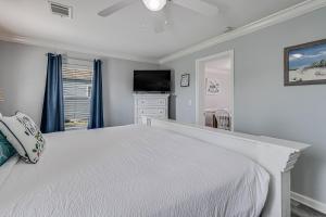 a white bedroom with a bed and a television at Sparrow's Nest in Rockport