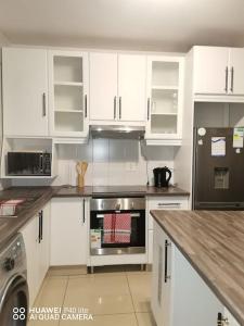 a kitchen with white cabinets and stainless steel appliances at Oliphant luxurious in Durban