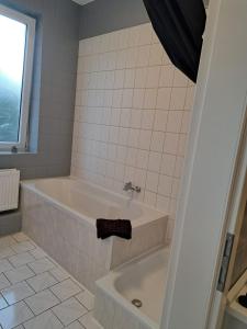 een witte badkamer met een bad en een wastafel bij Flensburg City 10 1 OG L in Flensburg