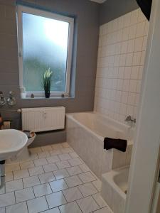 een badkamer met een wastafel, een bad en een raam bij Flensburg City 10 1 OG L in Flensburg