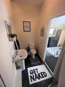 a bathroom with a toilet and a sink with a get wanted sign at Beautiful 1 Bedroom Maisonette in Leicester