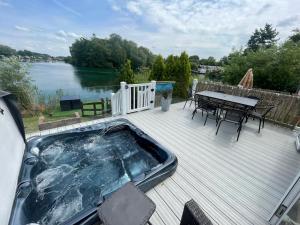 a hot tub on a deck with a table and chairs at Lakeside Retreat 1 with hot tub, private fishing peg situated at Tattershall Lakes Country Park in Tattershall