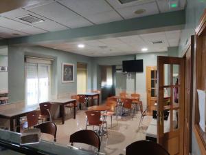 a room with tables and chairs and a flat screen tv at Hotel Dora in Plasencia