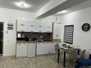 kuchnia z białymi szafkami i stołem z krzesłami w obiekcie Daniel Apartment w mieście Năvodari