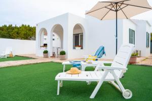 een patio met 2 stoelen en een parasol bij Apartamento Calan Bosch, Ciutadella in Cala'n Bosch