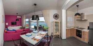 cocina y sala de estar con sofá rosa y mesa en Villa Rogoznica, en Rogoznica