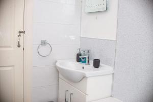 La salle de bains blanche est pourvue d'un lavabo et d'un miroir. dans l'établissement Entire Fabulous 2Bedroom First Floor Flat Located Within Close Proximity to City Centre & University of Aberdeen with Private Parking, à Aberdeen