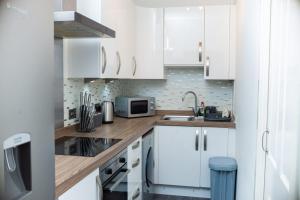 eine Küche mit weißen Schränken und einer Spüle in der Unterkunft Entire Fabulous 2Bedroom First Floor Flat Located Within Close Proximity to City Centre & University of Aberdeen with Private Parking in Aberdeen