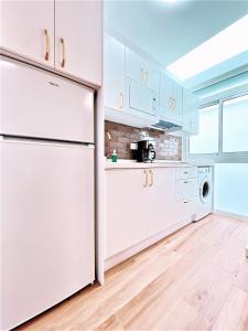 a kitchen with white cabinets and a refrigerator at Apartamentos Pepita in San Sebastián de la Gomera