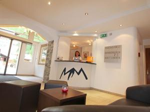 a woman standing behind a counter in a waiting room at Hotel Monte-Moro in Saas-Almagell