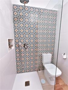 a bathroom with a toilet and a tile wall at Apartamentos Pepita in San Sebastián de la Gomera