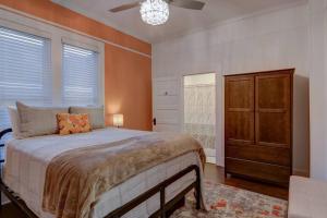 a bedroom with a bed and a dresser and windows at NEW! Orange Street Downtown Cottage in Hot Springs