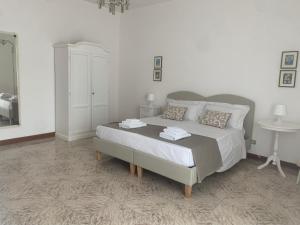 a white bedroom with a bed and a table at Porta Napoli Rooms in Lecce