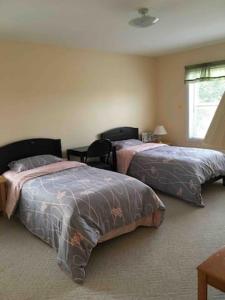 a bedroom with two beds and a table and a window at Lica’s house in Vernon Bridge