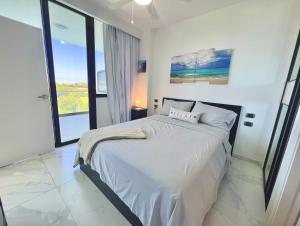 a bedroom with a white bed with a large window at Cana Rock Star, Apartamento Lujo Vista Golf Infinity Pool A-410 in Punta Cana