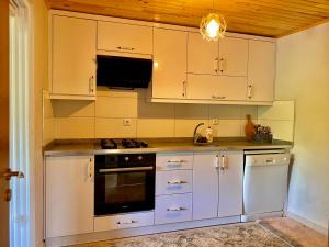 uma cozinha com armários brancos e um forno com placa de fogão em Persembe House em Aybastı