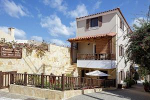 un edificio con un balcón con una sombrilla delante de él en Pension Lucy en Panormos Rethymno