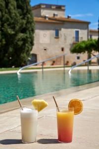 two drinks on a table next to a pool at URH - Hotel Molí del Mig in Torroella de Montgrí