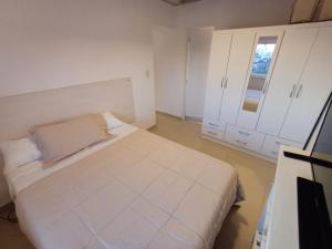 a white bedroom with a bed and a window at Atardeceres in Resistencia