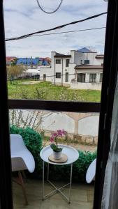 uma mesa com um vaso na frente de uma janela em Cozy villa, close to the center of Bucharest. em Bragadiru