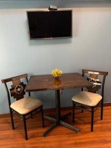 une table en bois avec deux chaises et une télévision sur un mur dans l'établissement Hotel Andina, à Cusco