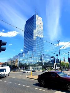 wysoki szklany budynek z samochodami na ulicy miejskiej w obiekcie Rooms by Kino Femina w Warszawie