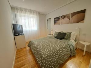 a bedroom with a bed and a flat screen tv at Panxón, a unos metros de la playa. in Nigrán