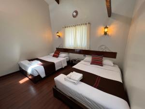 une chambre avec deux lits, une fenêtre et deux lampes dans l'établissement Hotel Andina, à Cusco