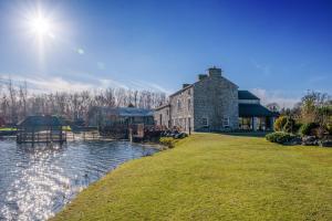 un gran edificio de piedra junto a un cuerpo de agua en Rambells Lodge, en Warton