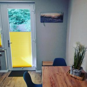 a dining room with a table and a yellow door at Apartment am Waldrand 1 Person Nichtraucher mit Einkaufsservice in Itzehoe
