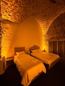 um quarto com 2 camas numa parede de tijolos em Paşaoğlu Konağı & Boutique hotel em Mardin
