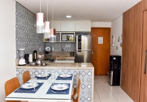 a kitchen with a table and a refrigerator at Carneiros Beach Resort Flat Térreo 2 quartos in Praia dos Carneiros