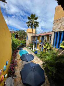 a patio with two umbrellas and a swimming pool at Pousada Girassol in Porto De Galinhas