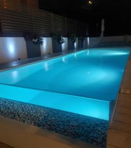 uma piscina iluminada à noite com pedras ao redor em Hotel Nettuno em Cala Gonone