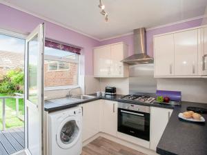 uma cozinha com paredes roxas e uma máquina de lavar e secar roupa em Hookhills Holiday Home em Goodrington