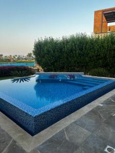 a swimming pool with blue water in a yard at Luxury villa in seachell sahel el alamein in Sīdī ‘Abd ar Raḩmān