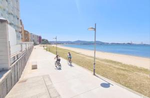 2 personnes à vélo sur un trottoir à côté de la plage dans l'établissement Piso con terraza en Villagarcia de Arosa, à Vilagarcía de Arousa