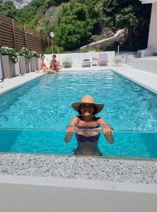 Una mujer con sombrero en una piscina en Hotel Nettuno, en Cala Gonone