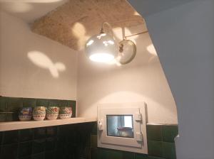 a bathroom with green tiles and a light and a mirror at Casa Vacanze Il Geco in Trani +16 photos