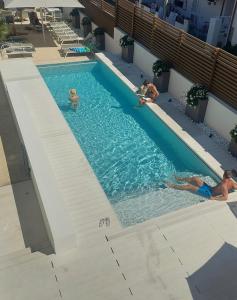 zwei Personen schwimmen in einem Pool in der Unterkunft Hotel Nettuno in Cala Gonone