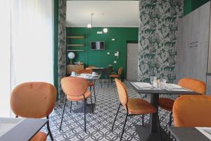 um restaurante com cadeiras e mesas cor de laranja e uma parede verde em Malù - Bed & Breakfast em Agrigento