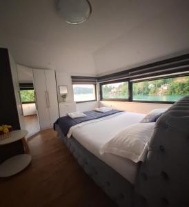 1 dormitorio con 1 cama blanca grande y ventanas en Apartment Hara, luxury lakeside suite with exquisite view en Jablanica