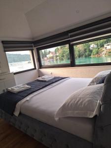 a large bed in a room with two windows at Apartment Hara, luxury lakeside suite with exquisite view in Jablanica +7 photos
