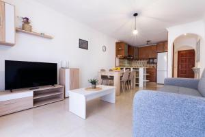 ein Wohnzimmer mit einem Flachbild-TV und eine Küche in der Unterkunft El Brezo in Tegueste