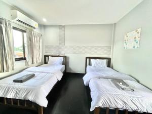 Habitación con 2 camas con sábanas blancas y ventana en J2 INN, en Uttaradit