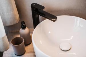 een wit toilet met een zwarte kraan en een beker bij Appartementhotel Seeblick in Gronau
