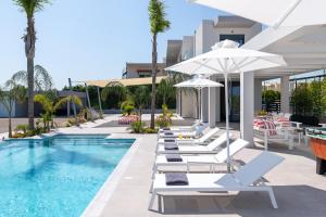 a pool with lounge chairs and umbrellas at Villa Korali in Pastida