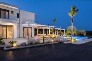 a large white building with palm trees and a swimming pool at Villa Korali in Pastida
