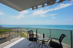 balcón con mesa, sillas y vistas al océano en RUMI Hotel en Batumi
