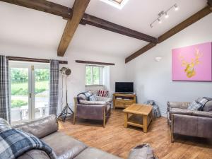 a living room with two couches and a tv at Teal Barn Annexe in Saint Weonards